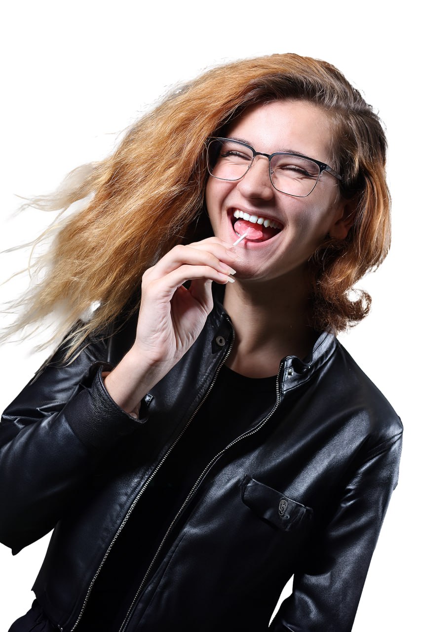Kolten Hesser smiling in glasses and a black jacket against a white background